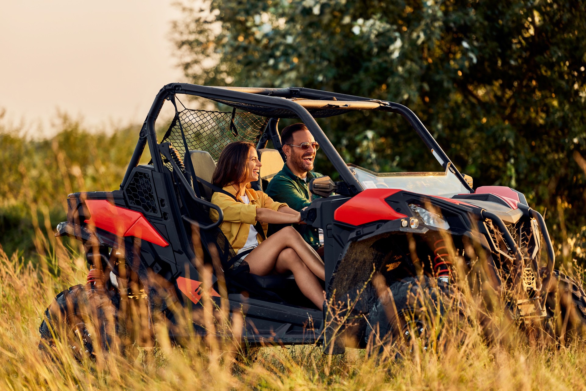 A smiling couple in love enjoying in drive on a quad bike off-road.